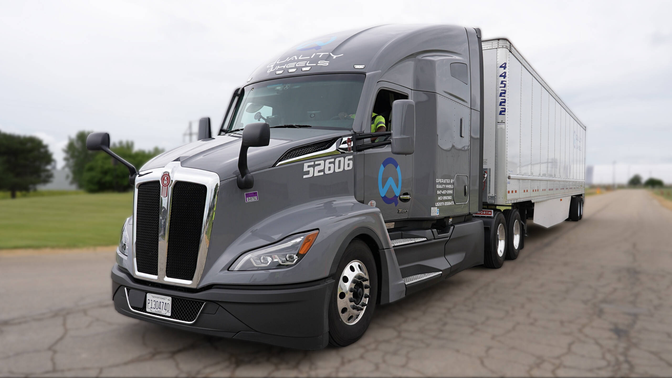 Grey Quality Wheels semi-truck with a dry van trailer ready for DOT inspections