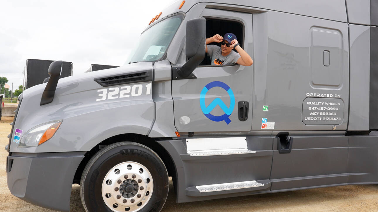 Quality Wheels Inc. CDL-A driver behind the wheel of a Kenworth semi-truck